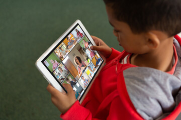 Poster - High angle view of biracial boy holding digital tablet studying online through video call at home