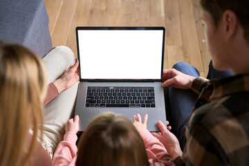 Happy family parents and kid child daughter using laptop computer mock up white screen sitting on couch at home doing ecommerce shopping online together. Over shoulder top view