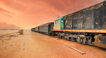 Old Unused Diesel Locomotive And Train At Wadi Rum Railroad Station, Sandy Desert Around, Pink Orange Toned Sky Background