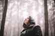 © Cavan Images - Portrait of happy young woman standing in forest during snowfall