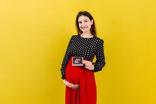 Cute Pregnant Lady Posing With Baby Sonography Photo Near Colored Background. Concept Of Pregnancy, Gynecology, Medical Test, Maternal Health