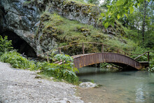 The Ancient Rock Entrance To The Cave Is A Wooden Bridge Over The River, Outdoor Recreation, Beautiful Landscape, Park Area In The Forest, Mountain Stream.