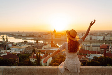 young female tourist enjoys the view of the city at sunset. back view. lifestyle, travel, tourism, n
