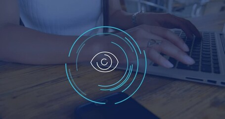 Poster - Animation of eye icon over caucasian businesswoman using laptop in office