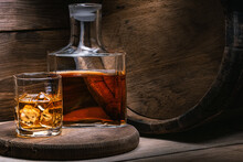 Bourbon Whiskey Is Strong Alcoholic Beverage Prepared By Irish Monk. Grain Whiskey From Scotland In Wooden Old Barrel Is Poured Whiskey Into Decanter And Glass Of Ice Of Amber Color.