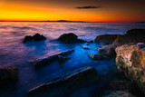 Fototapeta Fototapety do łazienki - Widok skał oblewanych przez morze o wschodzie słońca przy kolorowym niebie