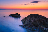Fototapeta Na sufit - Widok skał oblewanych przez morze o wschodzie słońca przy kolorowym niebie