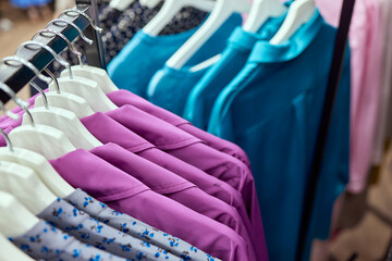 Clothes hang on a shelf in a designer clothes store.