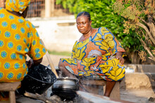 Candid Image Of African Women Cooking Out Door- Seated Black Women In Local Outdoor Kitchen