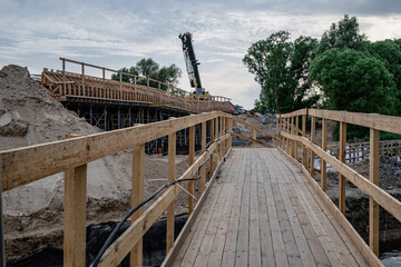 bridge construction site over small river in Latvia. Temporary wooden pedestrian bridge over the river