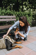 © shchus - A female veterinarian, a doctor helps a Rottweiler dog in a special corset to recover from an operation while sitting in the park. Animal photography.