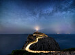 Leinwandbild Motiv Night time image with milky way stars and illuminated road with light trails at the Far de Formentor lighthouse on Mallorca, Spain