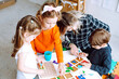 © Татьяна Волкова - Little kids with educator folding colorful details of constructor on desk in playroom from above view. Interesting game for kindergartners developing logic and intelligence. Communication with peers