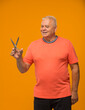 © serhii - an elderly man with scissors in his hands cuts something on a yellow background isolated