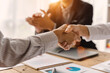 © Phushutter - Close up of female and male shaking hands, businessman and businesswoman handshaking at office table with charts graphs after successful negotiations, partners concluding contract.