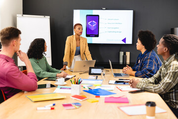 African american female manager discussing ideas with app developers in meeting at office