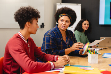 Biracial app developers discussing over color swatch during meeting in board room