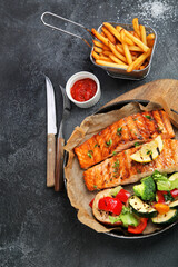 Canvas Print - Salmon steak with vegetables on dark background.