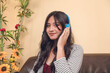 A young and attractive Filipina online teacher working at her living room. Wearing a blue wired headset.