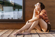 © sval7 - a girl with a dreadlocked hairstyle poses on the beach in summer against a red brown wooden wall, bright sunlight, dressed in a plaid shirt and shorts