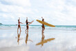 Group of Asian woman surfer in swimwear holding surfboard walking together on tropical beach at summer sunset. Female friends enjoy outdoor activity lifestyle water sport surfing on travel vacation