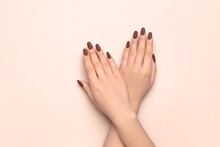 Crossed Female Hands With Beautiful Brown Manicure On Light Background