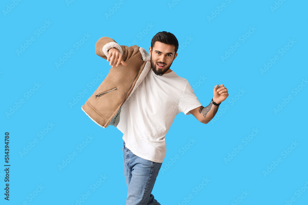 Young bearded man with stylish winter jacket on blue background