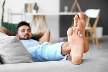 Young Barefoot Man Lying On Sofa At Home, Closeup