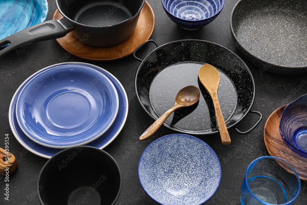 Stylish dinnerware and kitchen utensils on dark table