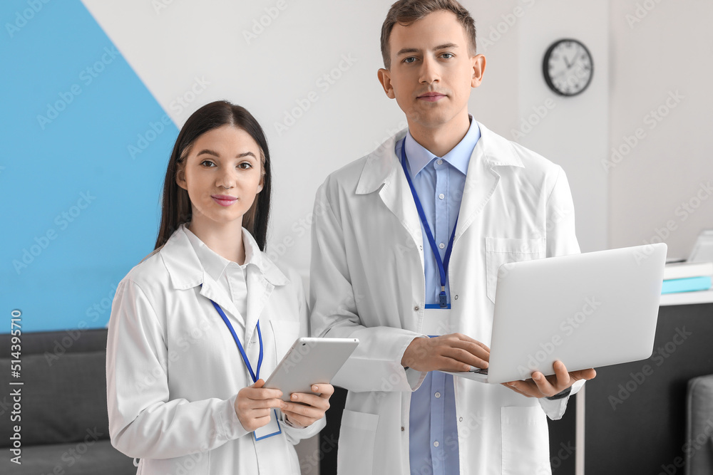 Medical assistants with tablet computer and laptop in clinic