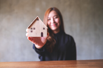 Wall Mural - A woman holding and showing a wooden house model