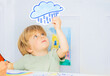 Boy in kindergarten class hold weather rain card