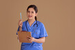 Young female nurse in blue scrubs with a stethoscope around her neck, holding a clipboard and pen