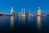 Fototapeta  - Rotterdam nighttime panorama with “Erasmus-Bridge“ over river Nieuwe Maas at evening blue hour in South Holland Netherlands. Waterfront with illuminated bridge and tall buildings on the waterfront.