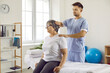 Professional chiropractor, osteopath or physiotherapist working with senior female patient. Male manual therapy specialist at modern health center massaging old lady's neck and shoulders