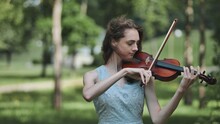 A Young Girl Plays The Violin In The City Park.