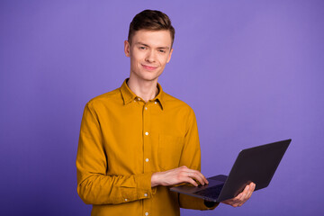 Portrait of attractive successful smart brunet guy holding laptop working isolated over shine color background