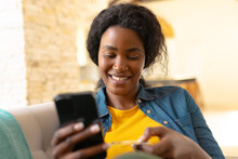 Smiling Young African American Woman Online Shopping Through Smart Phone At Home, Copy Space