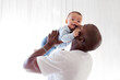© Anna Zhuk - African American dad kisses, holds on arms and loves baby son mixed race child against white background