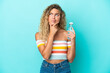 Young blonde woman with a bottle of water isolated on blue background having doubts