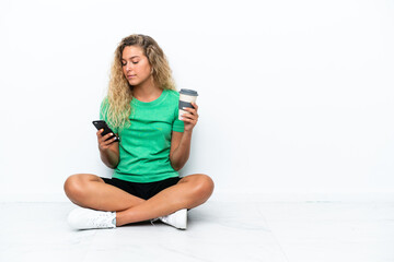 Wall Mural - Girl with curly hair sitting on the floor holding coffee to take away and a mobile