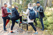 © Татьяна Волкова - Group of senior people learning to make Nordic walking with trekking stick in forest, stand one leg on bench. practicing