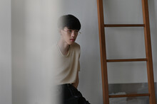 Portrait of Asian slim male,cross-dresser with crop-top shirt lonely sitting in the modern room with sad eyes. Homosexuality modeling concept.