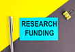Leinwandbild Motiv RESEARCH FUNDING text written on sticky with pen on grey, yellow background, business concept
