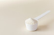A scoop with hydrolyzed collagen powder on a beige background. The concept of food additives, healthy. Copy space