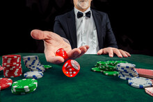 Gambling Concept. Close Up Of Male Hand Throwing Dice At Casino, Gambling Club. Сasino Chips Or Casino Tokens, Poker Cards, Gambling Man Spending Time In Games Of Chance