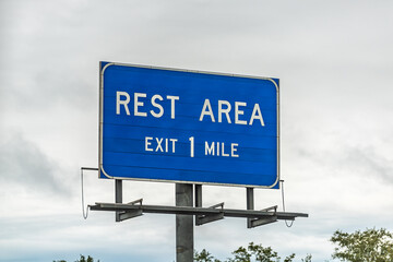 Blue color sign isolated closeup for rest area stop right exit in one mile in Sparks, south Georgia on interstate highway 75 with cloudy sky in background