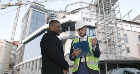 Male developer giving keys to owner at building site