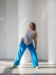 © Ulia Koltyrina - Youth jazz-funk dance style. Young and free, dancing in baggy clothes in a bright white hall. Stylish brunette in blue pants in a dynamic pose