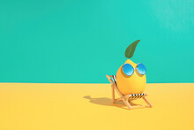 Lemon Fruit Chilling In Beach Chair On The Blue And Yellow Background. Summer Vacation Concept. Sunglasses On Lemon With Green Leaf Relaxing On The Sunbed. Creative Art Minimal Aesthetic.